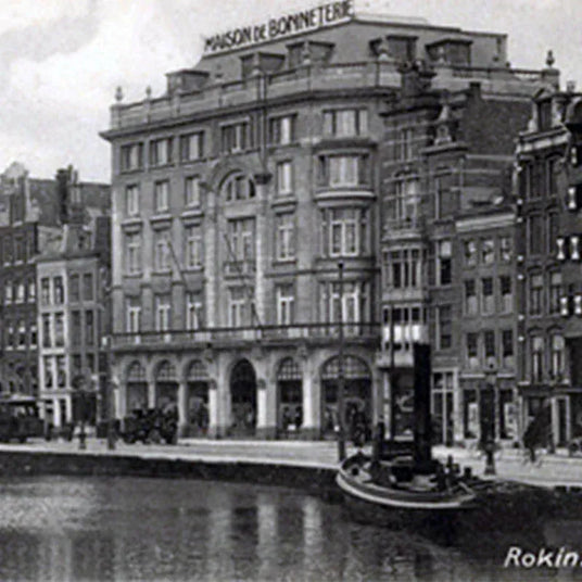 Historische zwart-witfoto van een klassiek grachtenpand met tekens van Maison de Bonneterie aan de Amsterdamse Rokin.