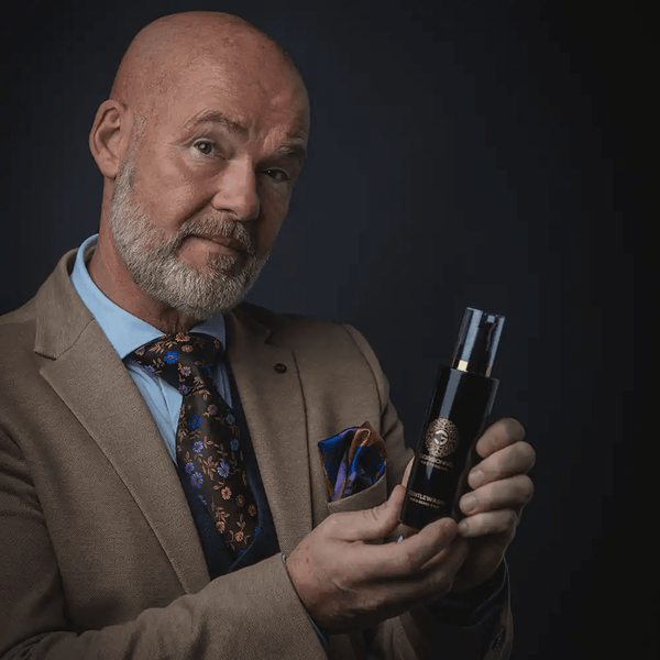 Zakelijke man met baard toont luxe elegant verpakt huidverzorgingsproduct tegen donkere achtergrond, focus op kwaliteit